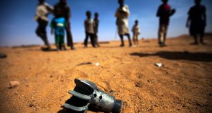 Un grupo de niños mira los restos de un obús en Sudán.