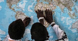 Dos menores migrantes de Gambia que cruzaron el Mediterráneo sin sus padres ven un mapa.