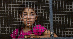 Una niña siria mira a través de una ventana desde el albergue para desplazados a donde llegó con su familia.