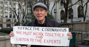 Un ciudadano de Nueva York con una pancarta en la que se lee: Para afrontar el coronavirus, debemos trabajar juntos y escuchar a los expertos.