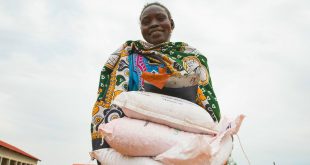 Mujer cargando costales de semillas distribuidos a las familias en Sudán del Sur durante la pandemia de COVID-19