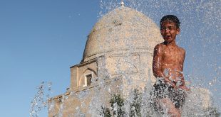 Un niño se refugia del calor en una fuente de la ciudad de Samarkand, Uzbekistán.